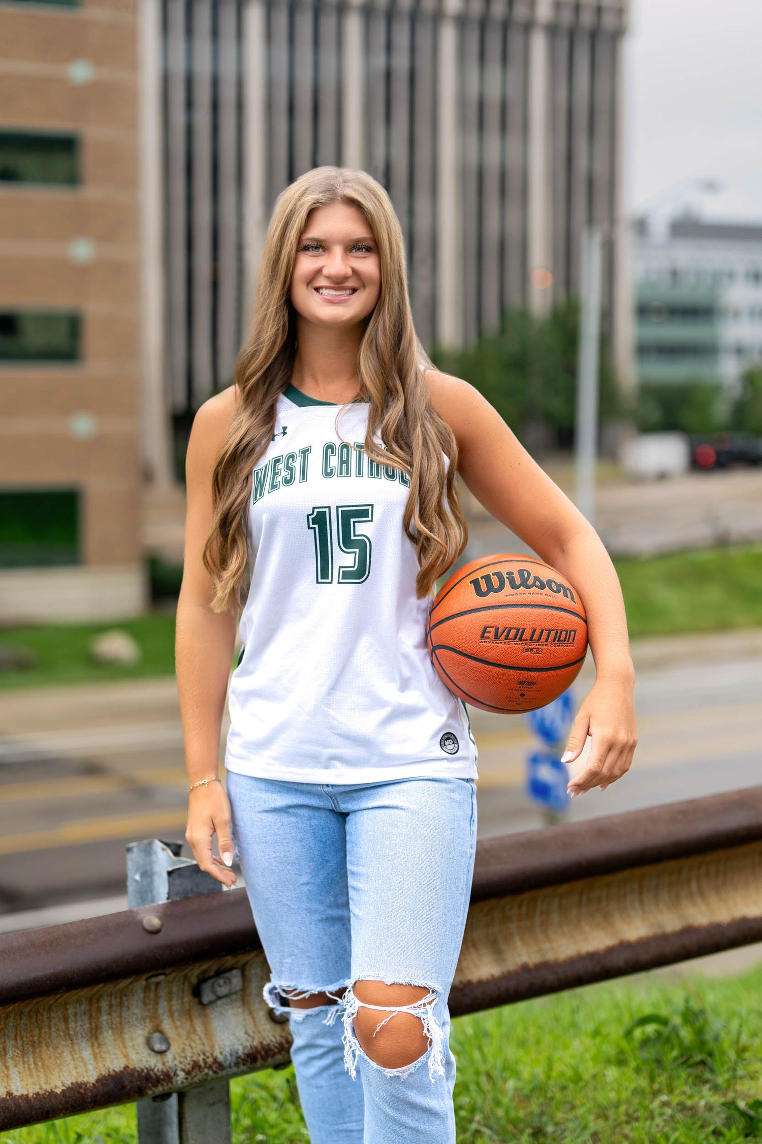 A basketball player in jersey number 15 poses with a Wilson basketball.