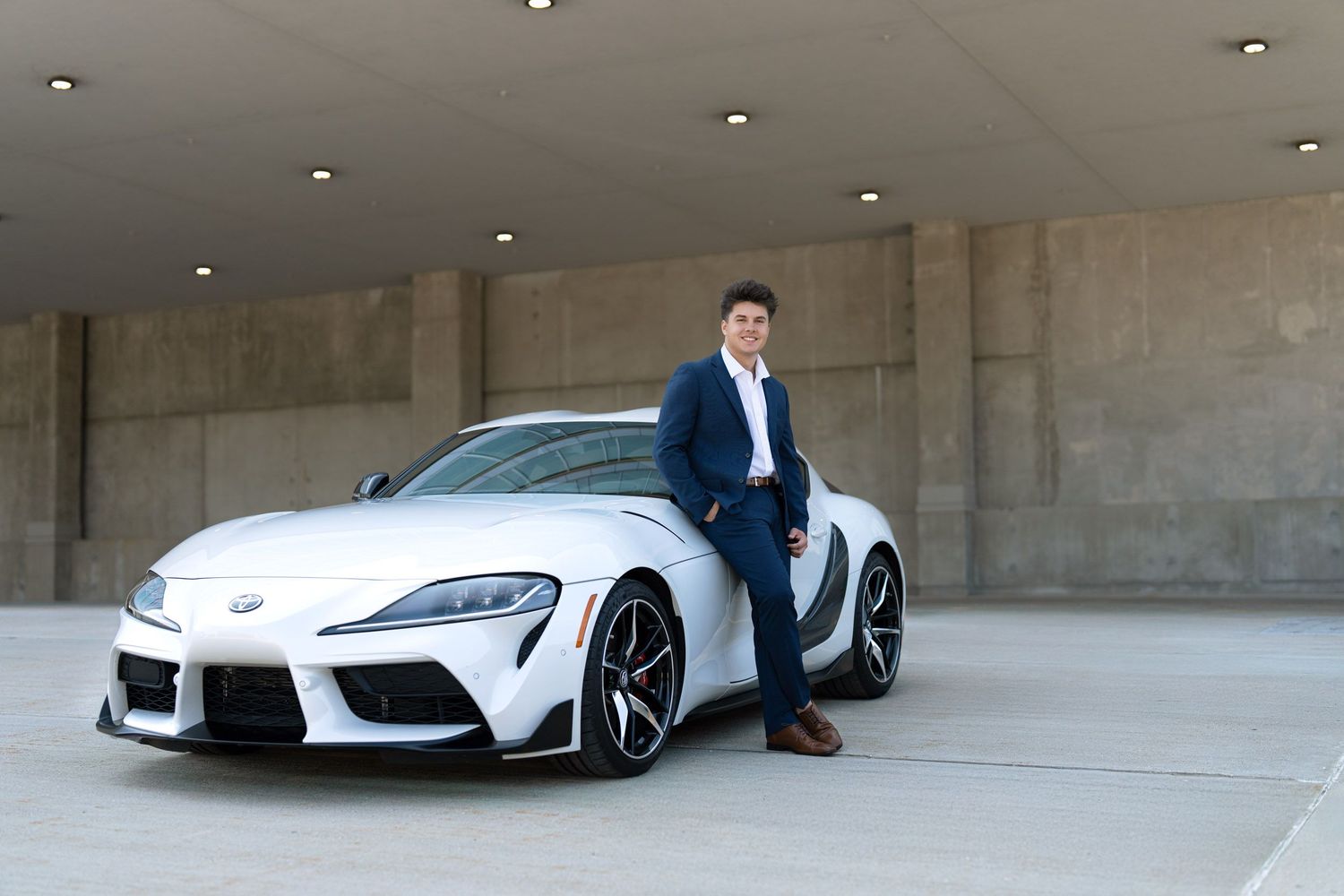 Creative senior pictures in Grand Rapids for guys featuring a white sports car and modern urban architecture.