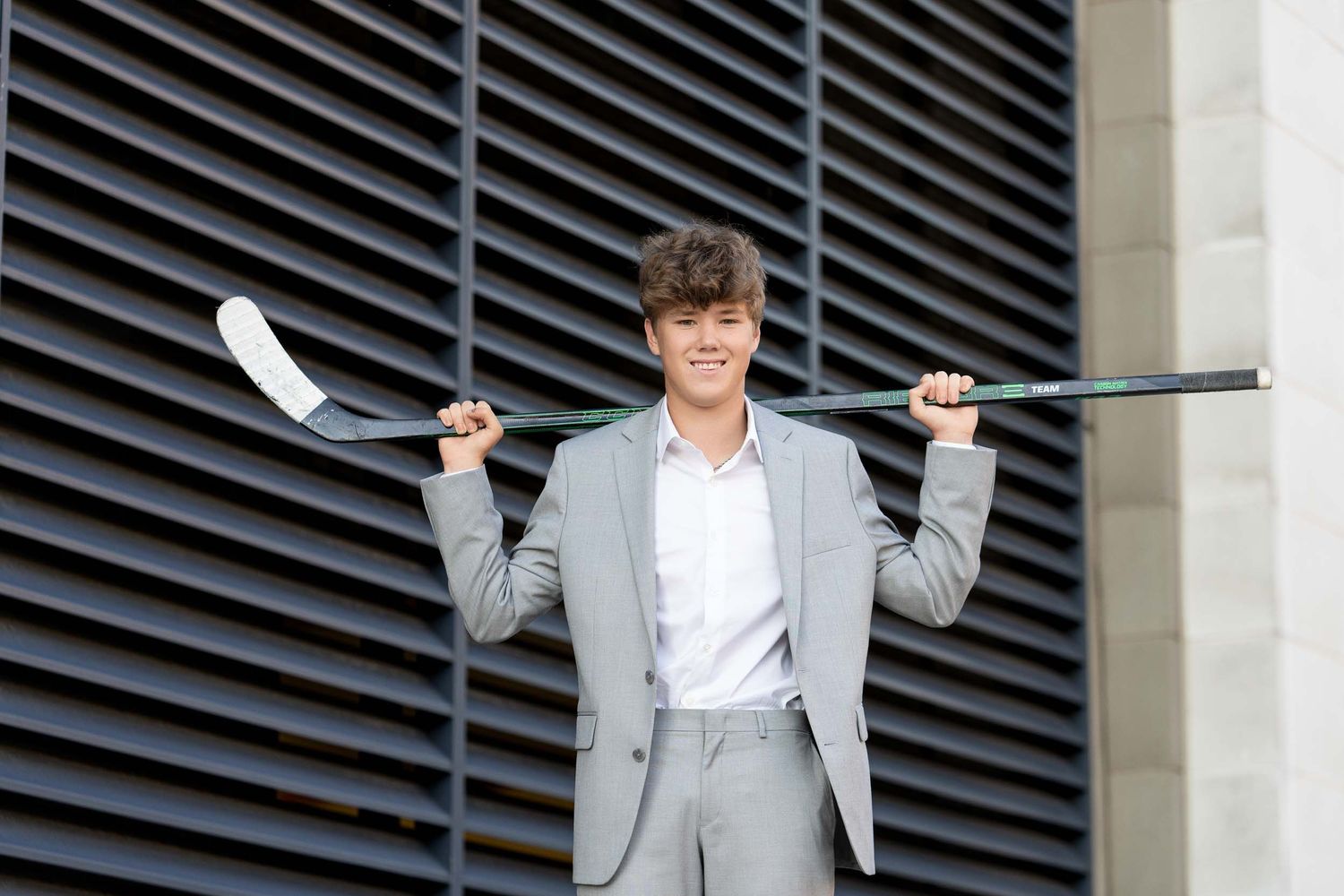 A person in a gray suit and white shirt poses playfully with a laptop in multiple sequential shots.
