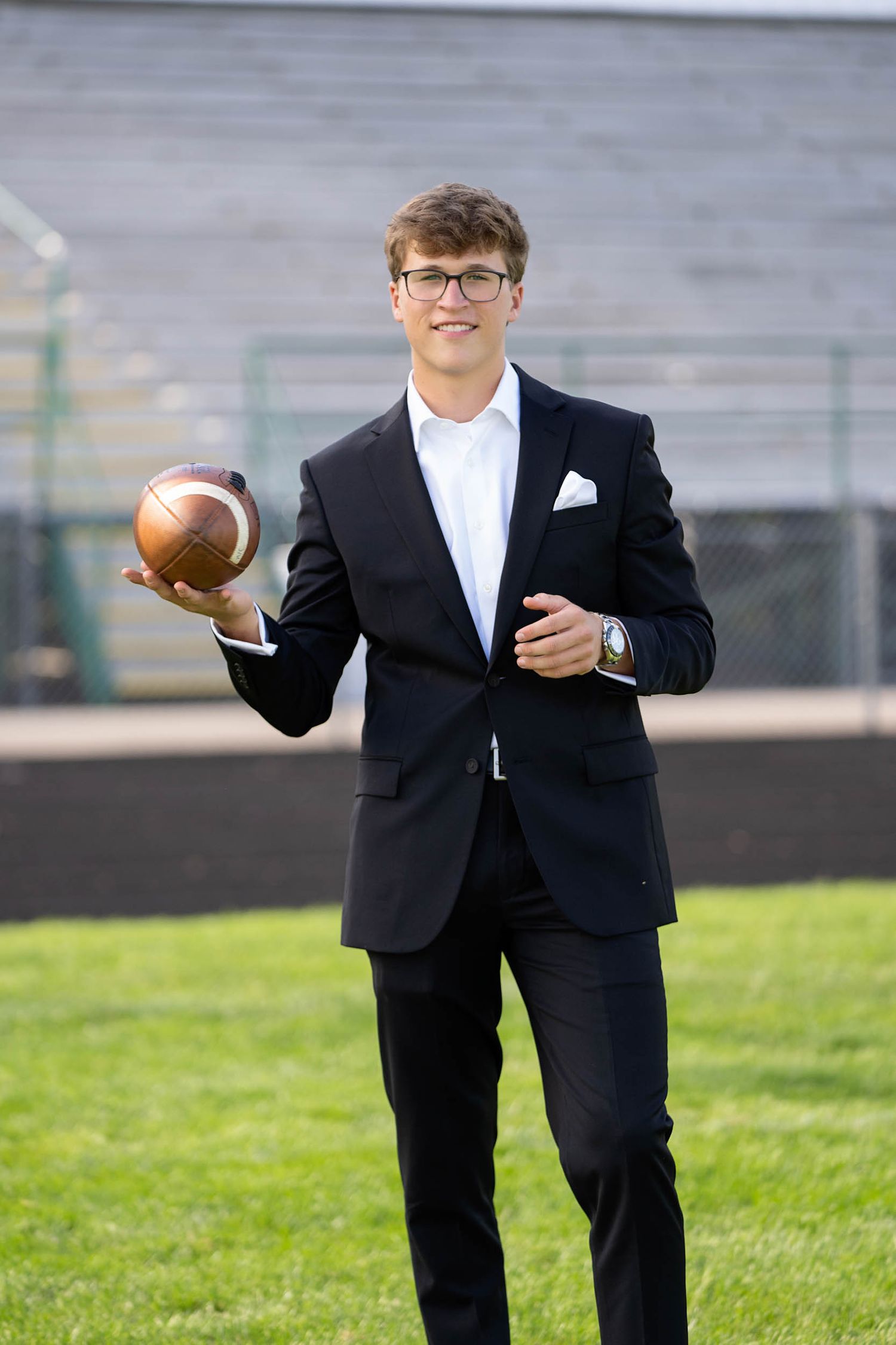 A person in a black suit holds a football on a grassy field, showing multiple poses in a sequence.