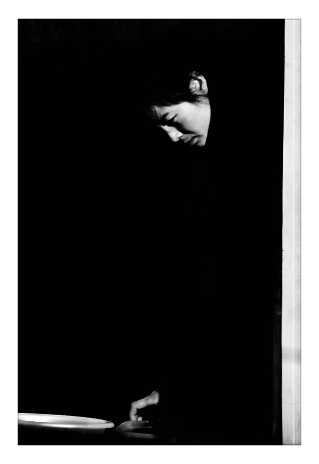 Black and white photo series showing hands carefully plating and preparing food on a dark background.