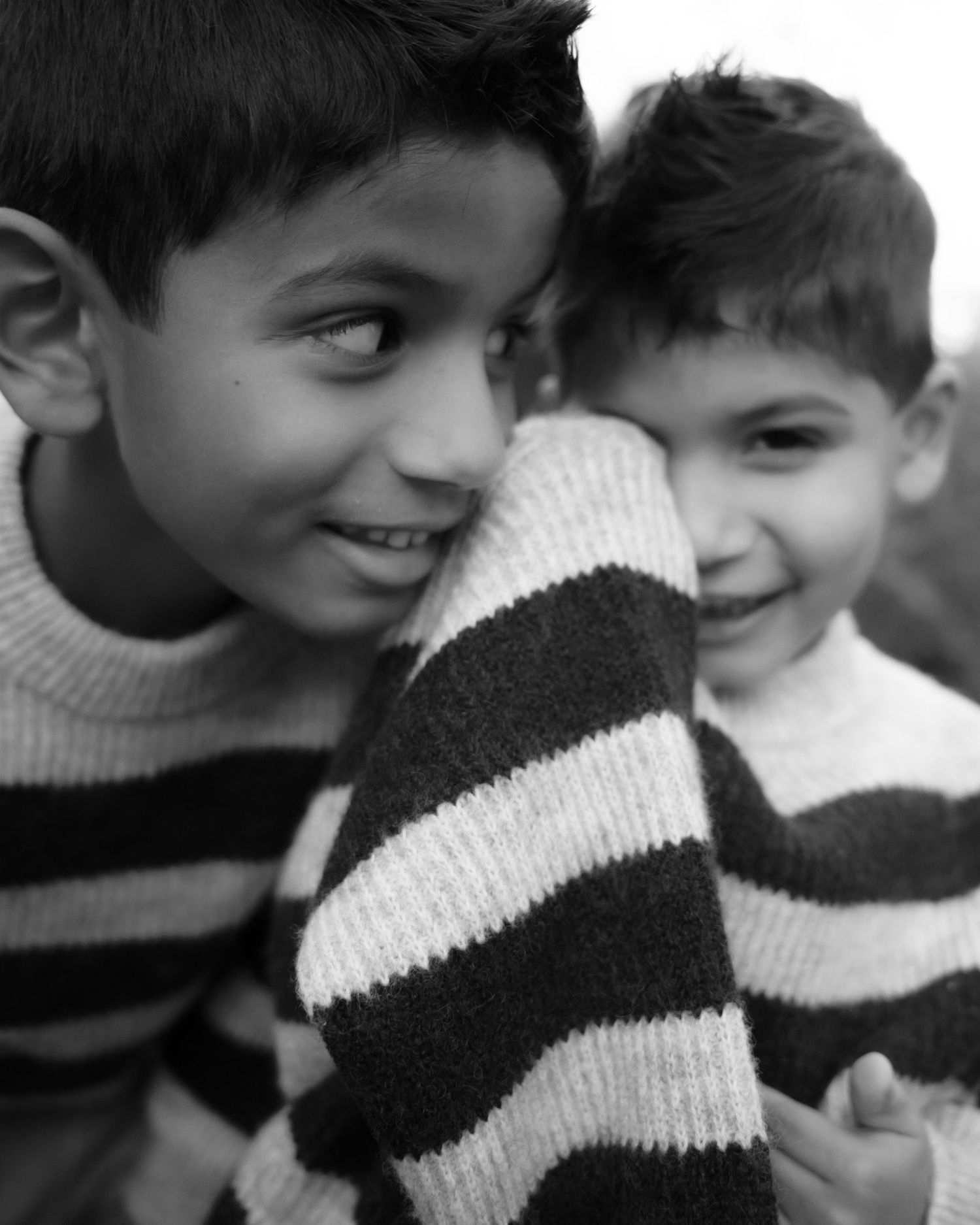 A black and white sequence of images showing two children in striped sweaters playfully interacting.