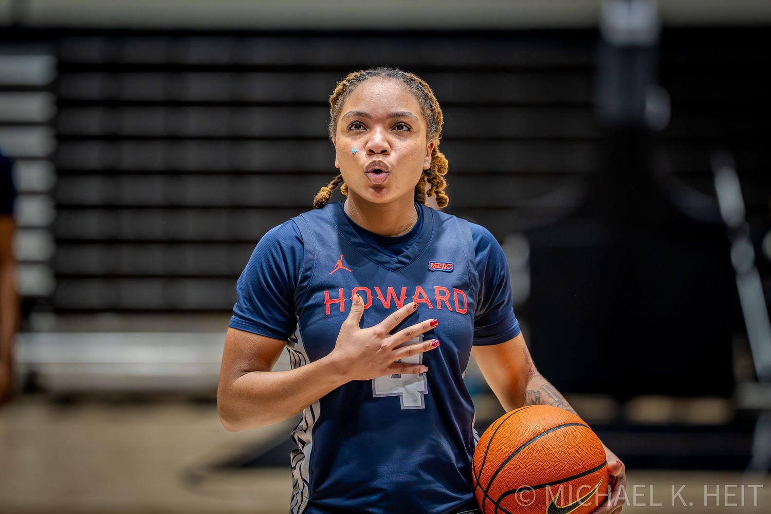 Basketball players in navy blue jerseys practice on the court during a team training session.