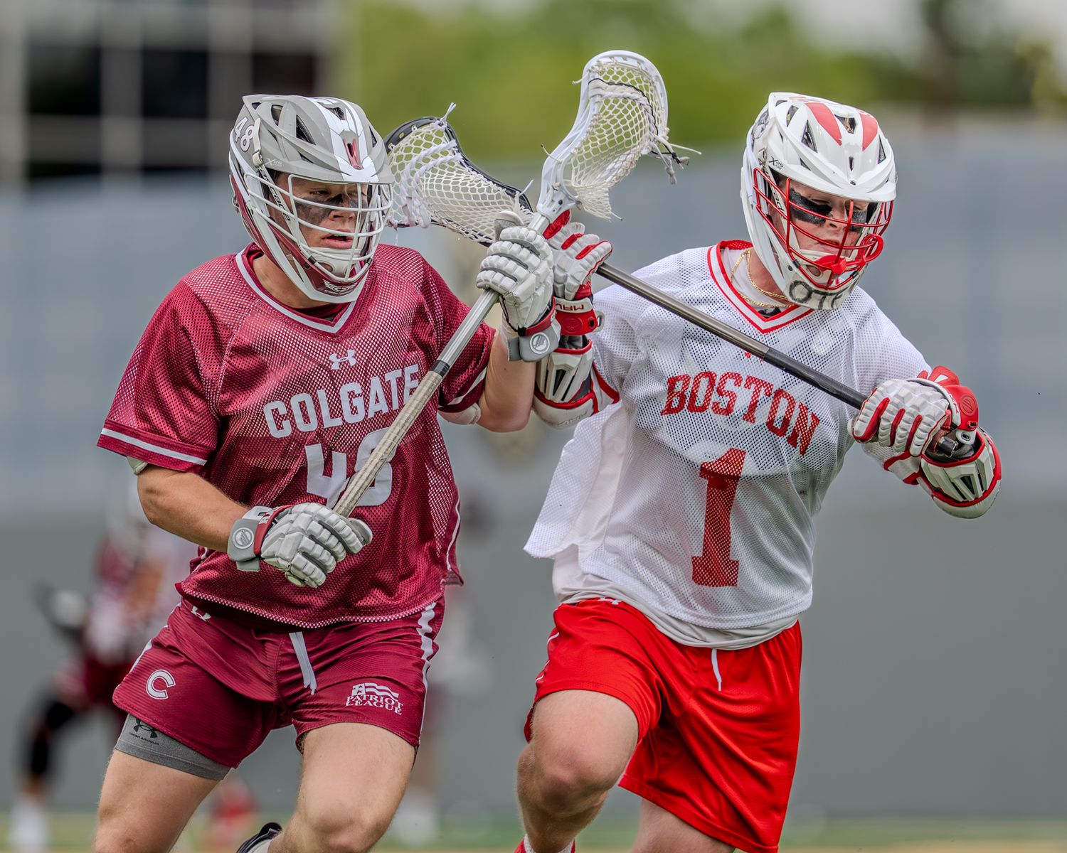 Boston University and Colgate lacrosse players engage in competitive gameplay on the field.