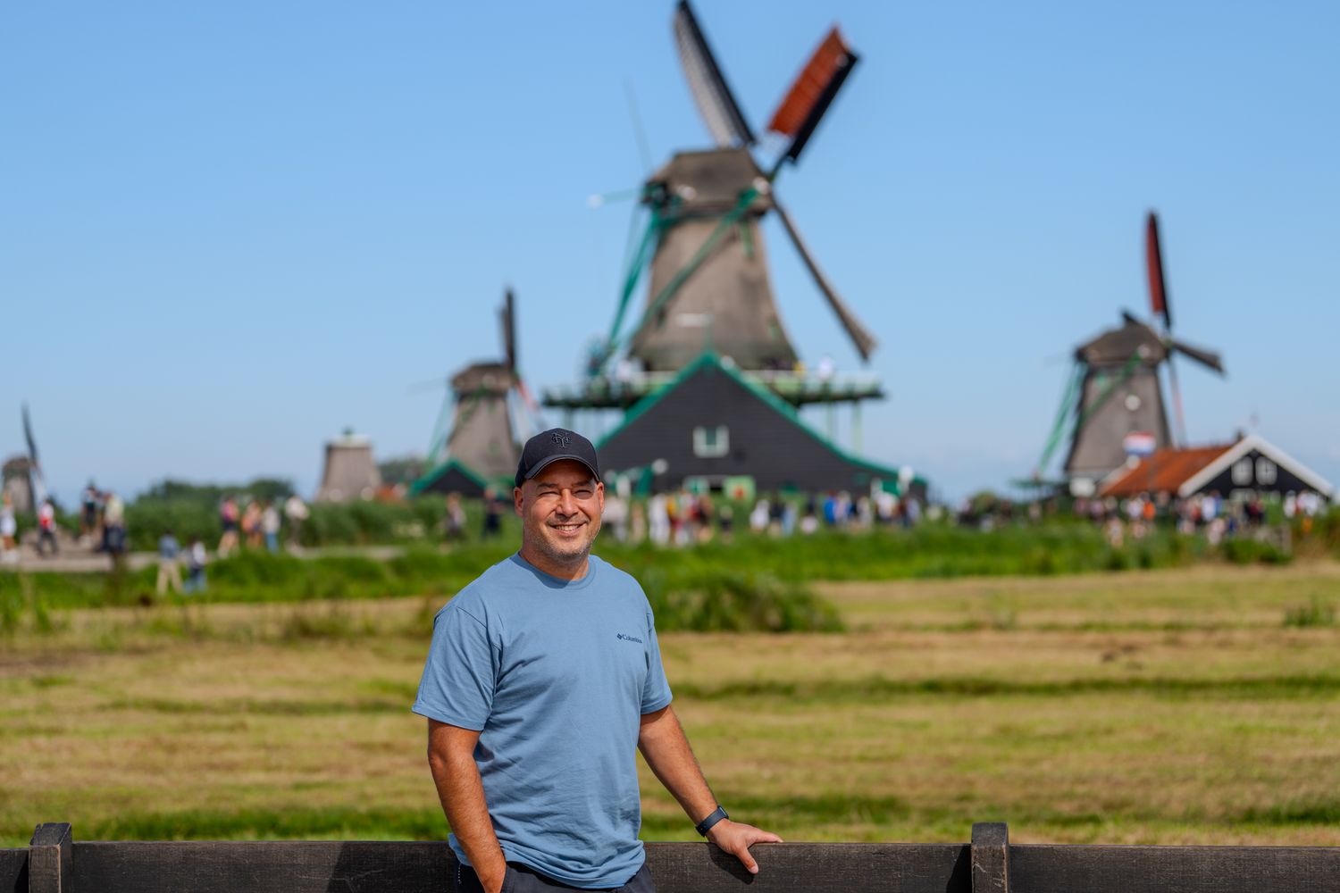 Traditional Dutch windmills line the horizon in a scenic rural landscape.