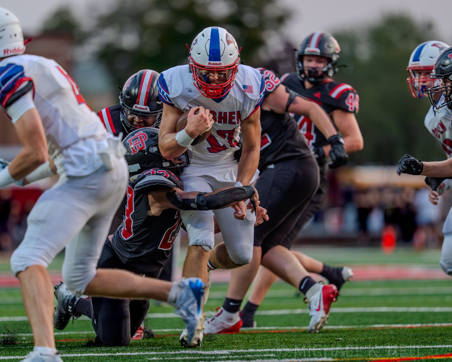 Football players from opposing teams battle at the line of scrimmage during an intense play.