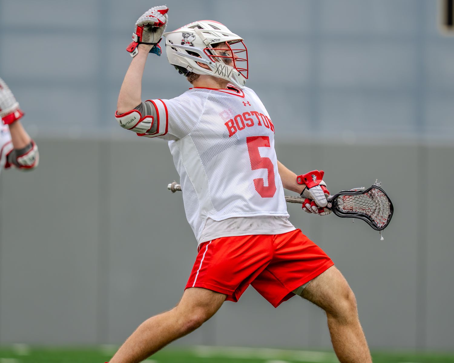Lacrosse player in white jersey maneuvers with the ball during collegiate match.
