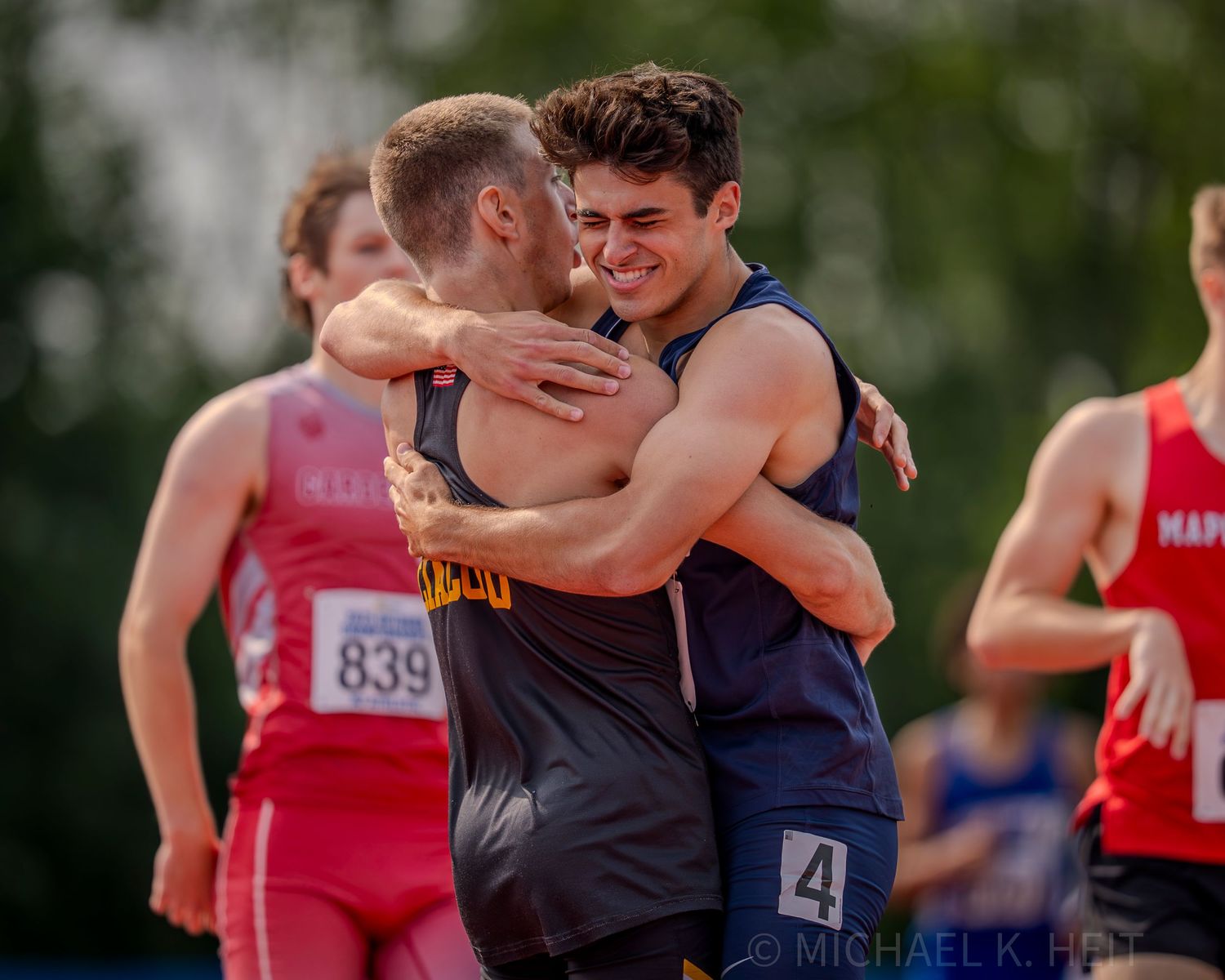 Track athletes embrace after competition showing sportsmanship and camaraderie.