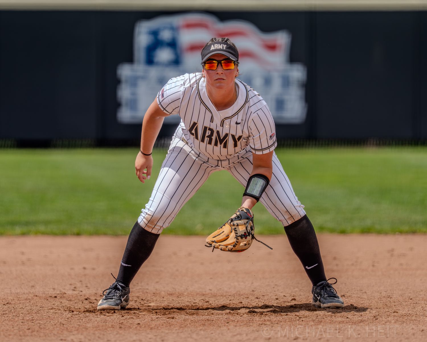 Baseball infielder in pinstriped Army uniform crouches in ready position on the field.