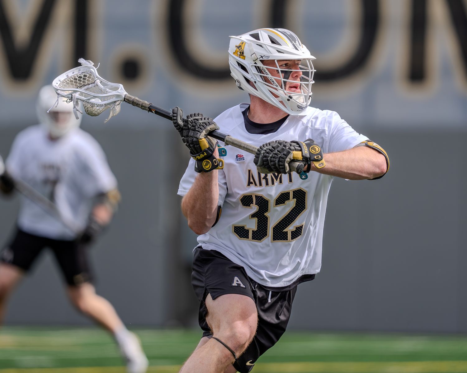 Army lacrosse player dodges defender during intense gameplay action.