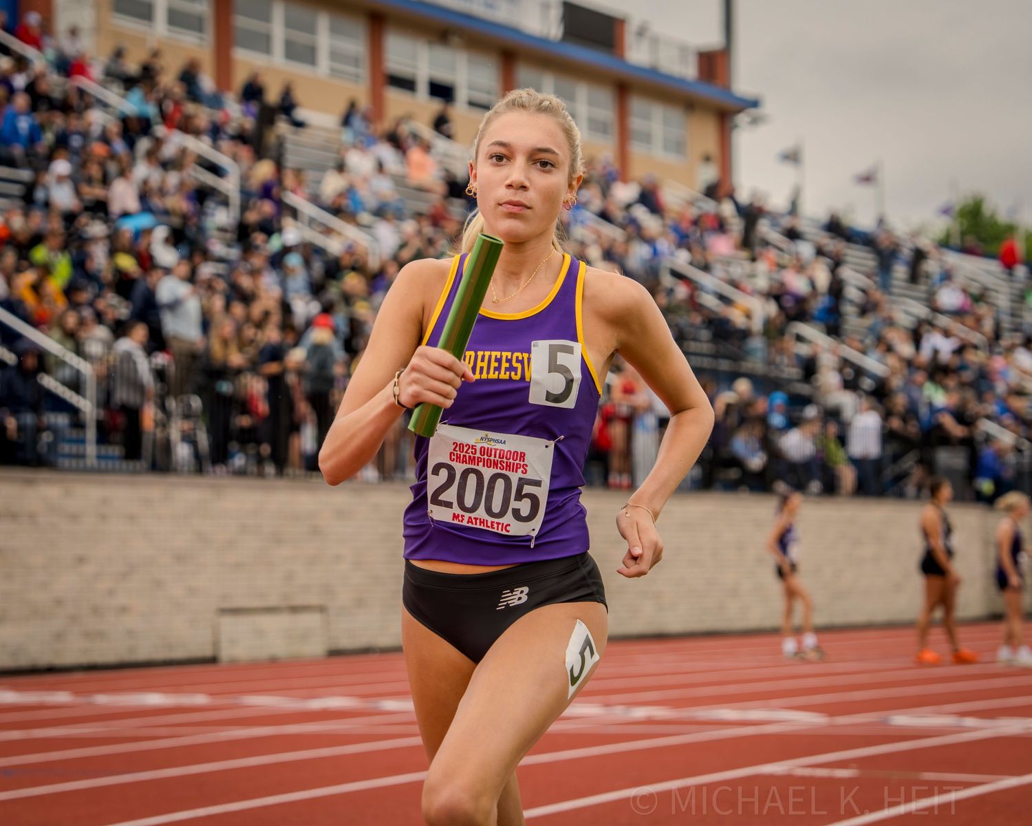 Runners race down the track during an outdoor competition.
