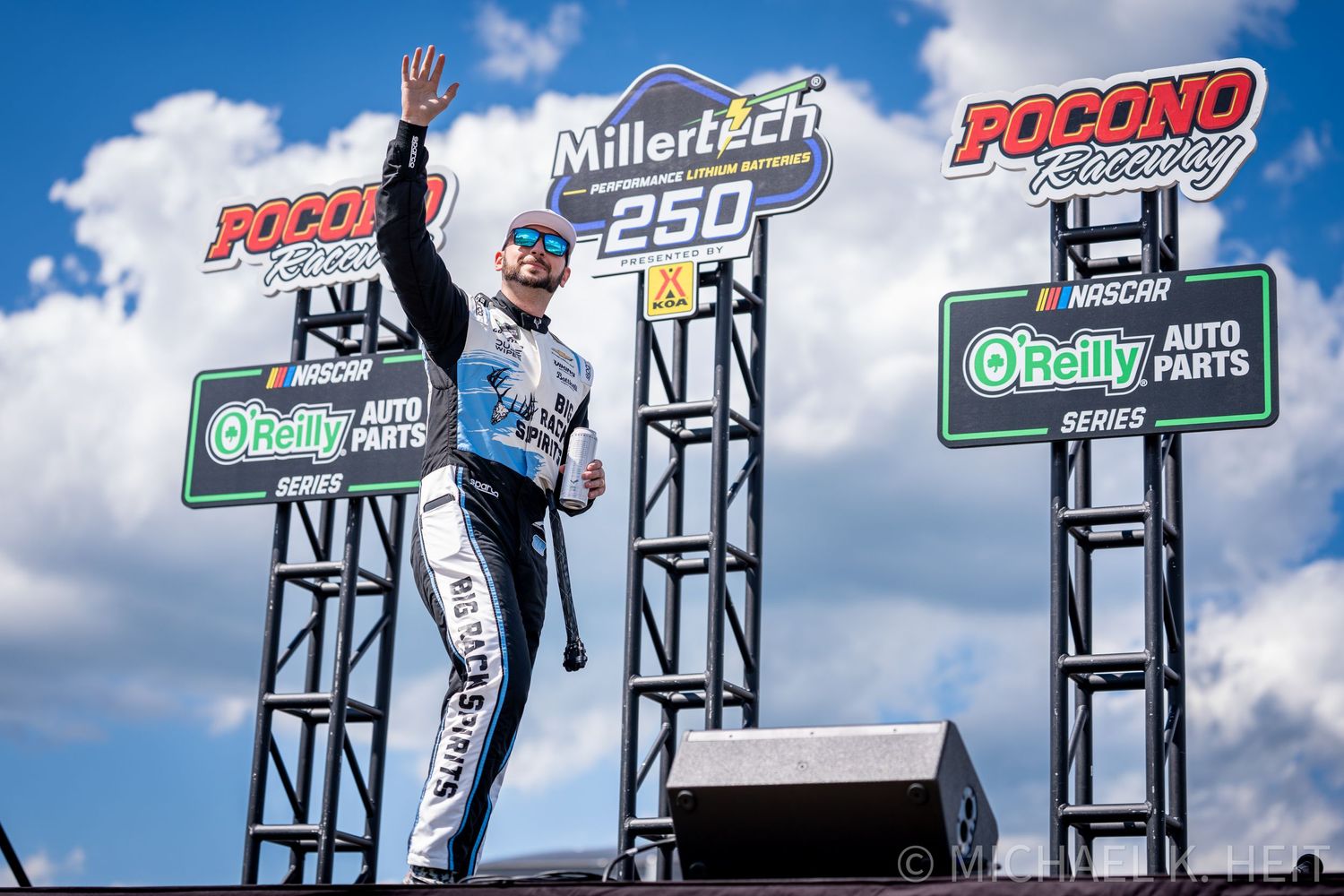 NASCAR driver waves to fans on victory podium at Pocono Raceway during the MillerTech 250 O'Reilly Auto Parts Series race.