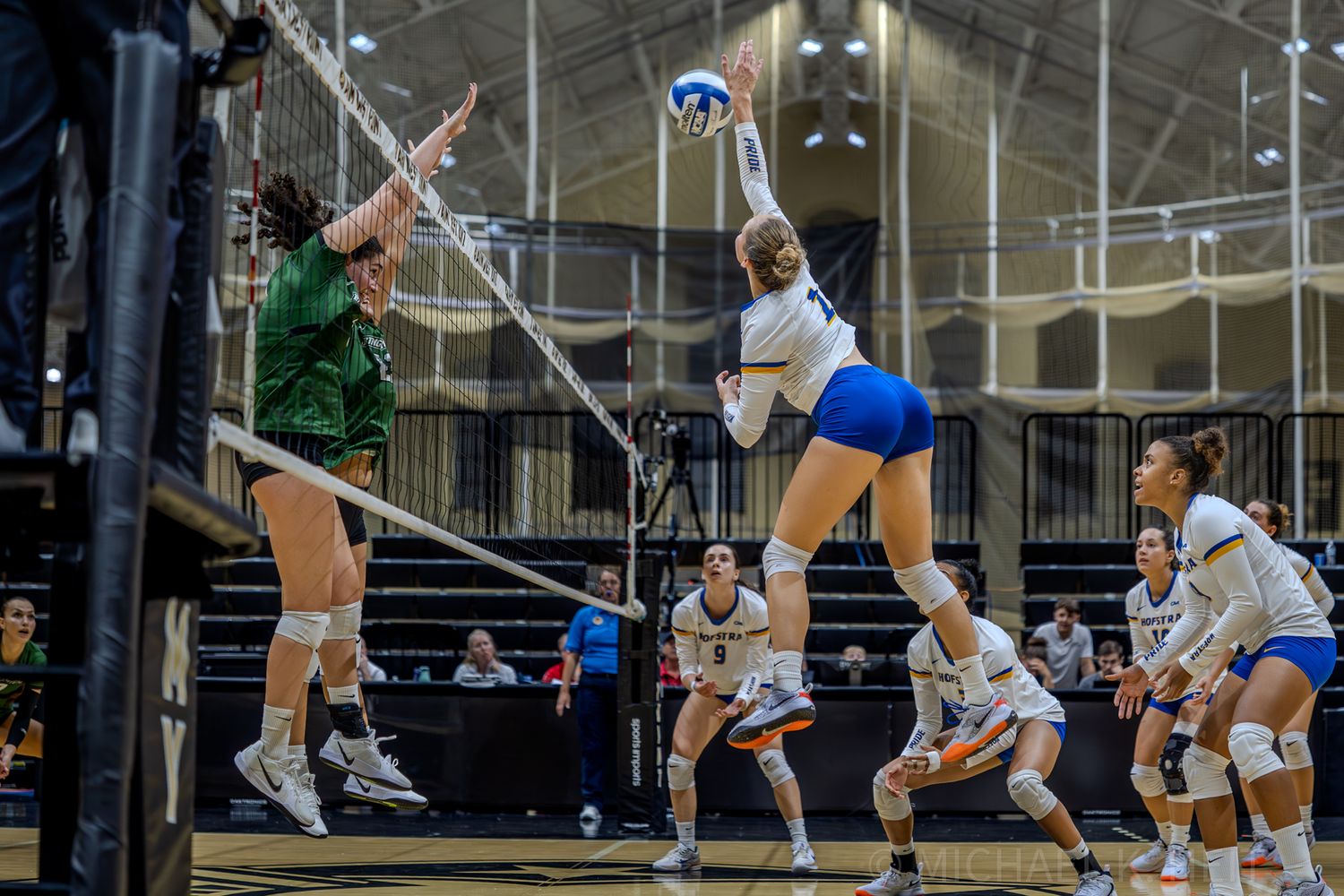 Athletes compete for the ball during an intense indoor volleyball match.