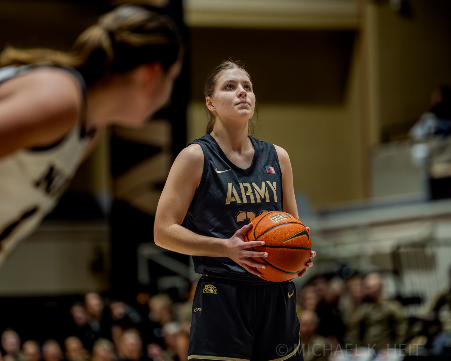 Army basketball player dribbles down the court during an intense game against Navy.