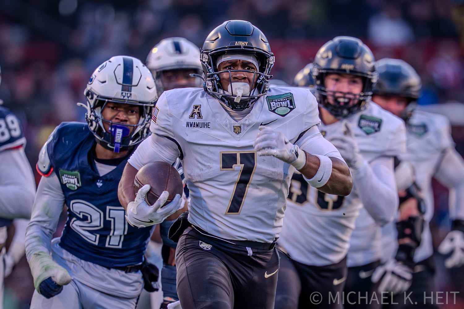 Football players in white and blue uniforms compete during an intense game action shot.