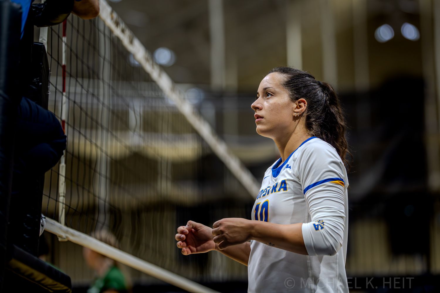 Players on the volleyball court prepare for action in defensive positions.