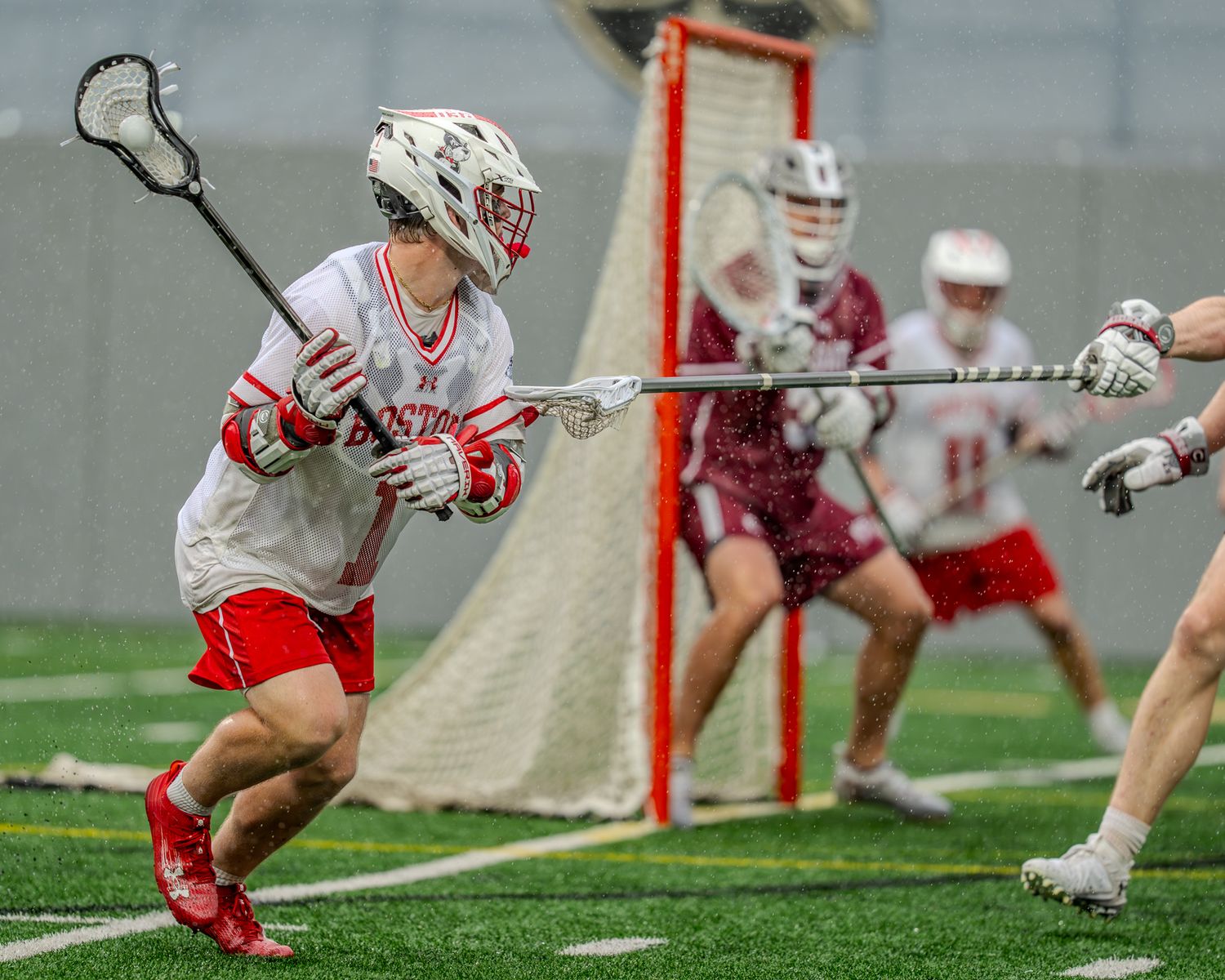 Close-up action shot of lacrosse players battling for ground ball possession during competitive match.