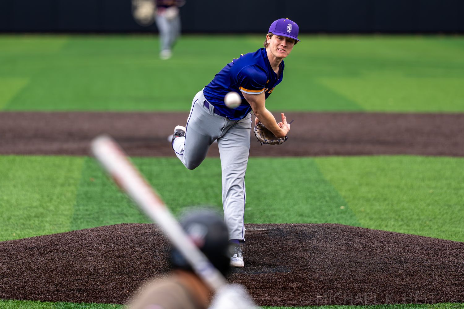 Baseball players execute different pitching and fielding positions during game action.