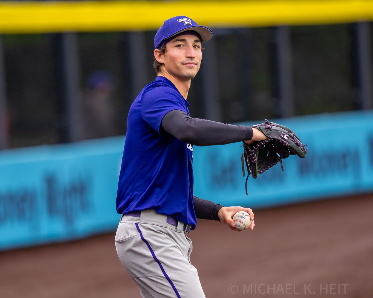 Baseball player in royal blue uniform throws pitch during game.