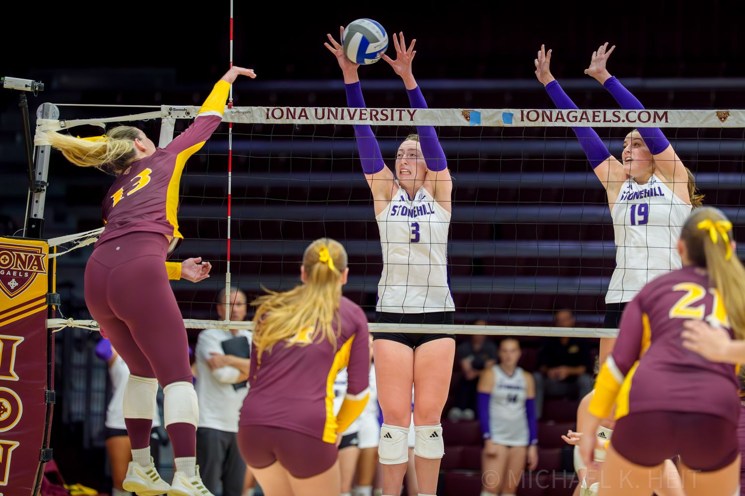 Players from opposing teams compete for the ball at the net during a volleyball match.