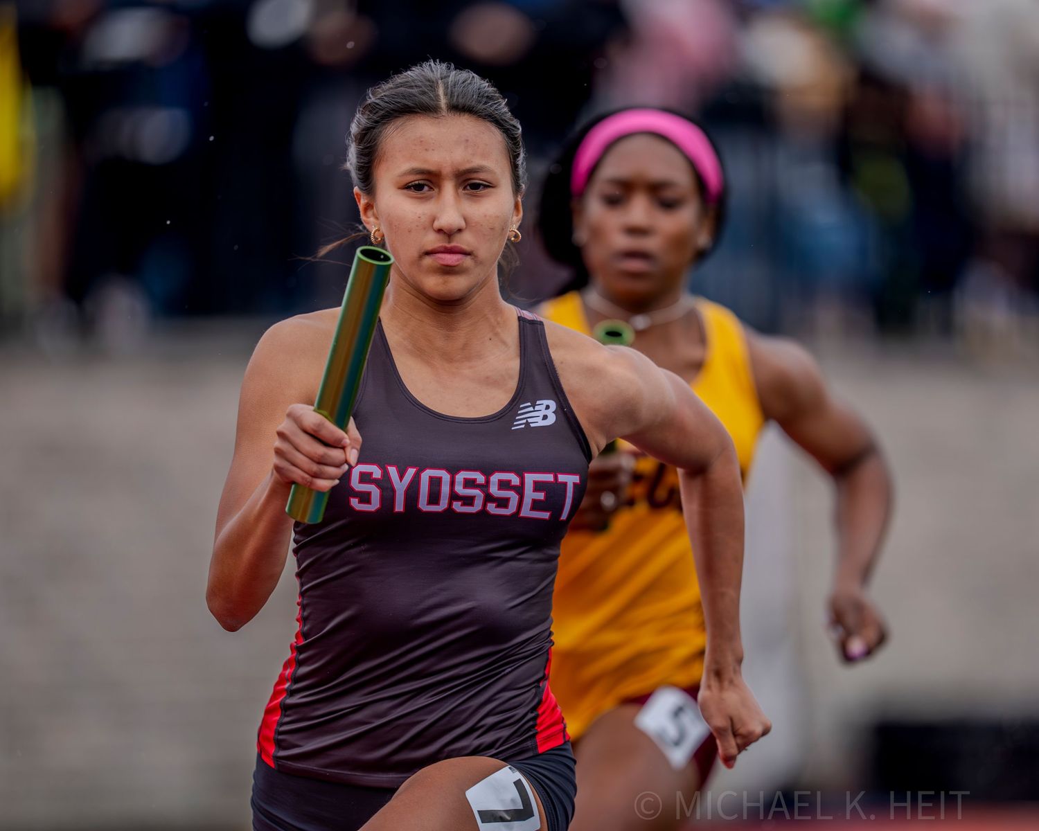 Athletes racing on an outdoor track during a competitive meet.