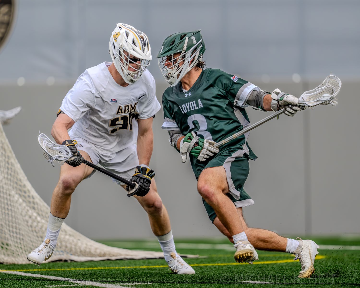 Intense ground battle between lacrosse players in green and white uniforms near the goal.