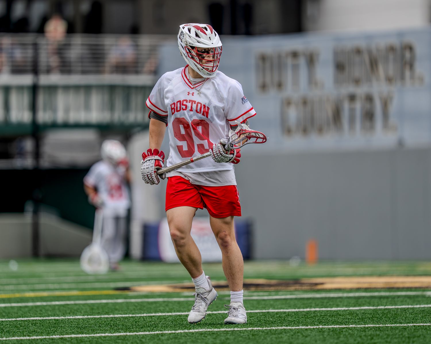 College lacrosse players compete on artificial turf during a competitive game.