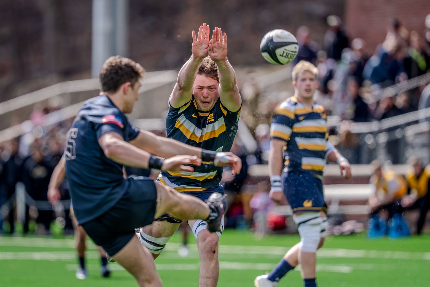 Rugby player attempts to block a kick during an intense match between two teams on the field.