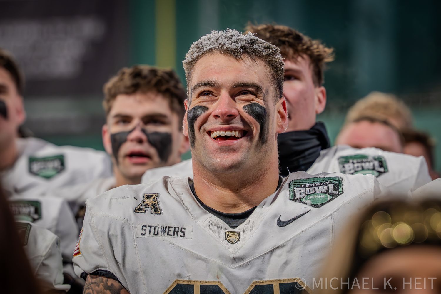 Michigan State football players celebrate and smile with teammates during an emotional victory moment.