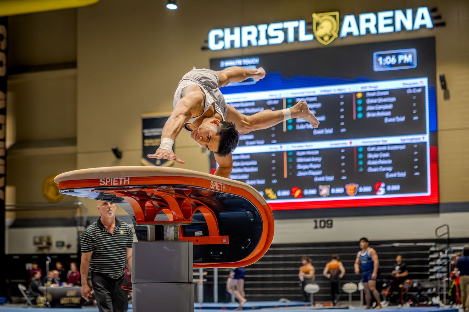Gymnast performing a vault at Christl Arena competition, captured mid-air above the vaulting table.