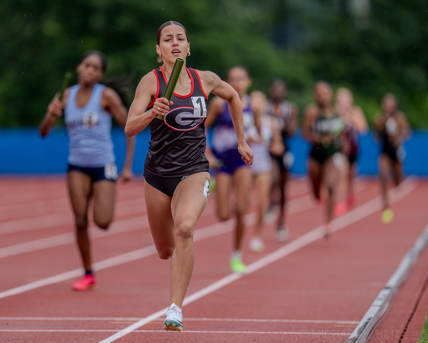 Athletes compete in long jump competition at outdoor track and field meet.