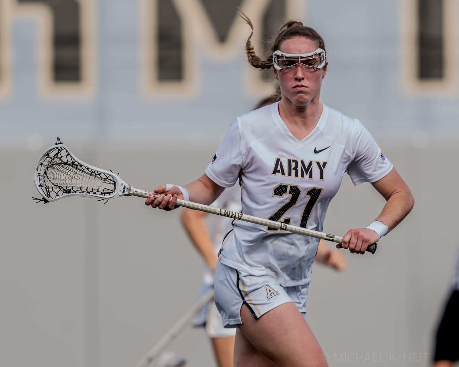 Lacrosse players in white uniforms compete during an intense match on the field.