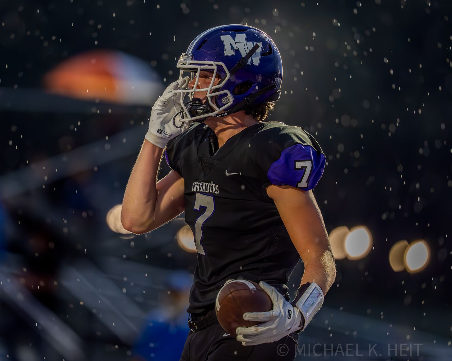 Football players battle in snowy conditions during a nighttime game.