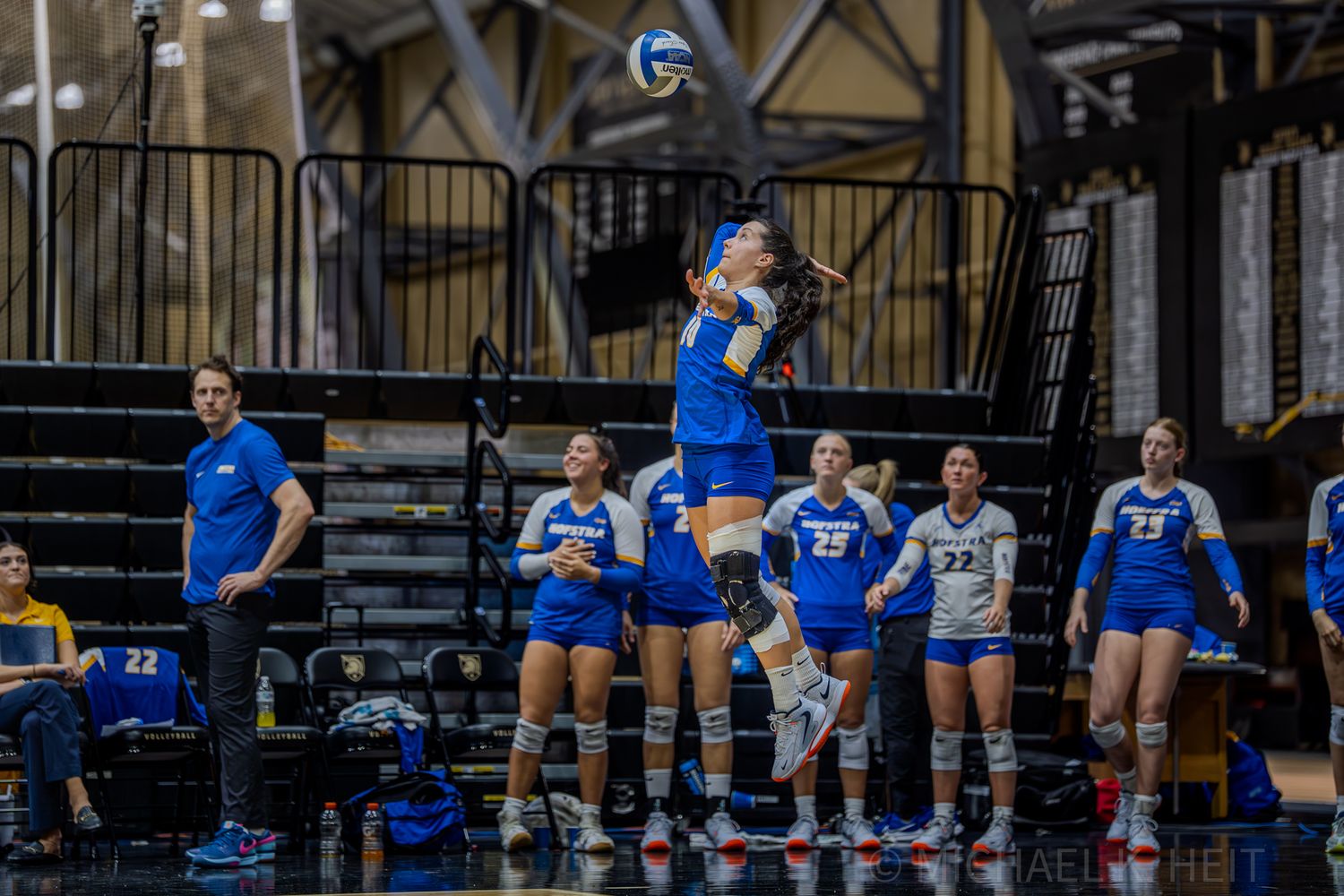Wide view of volleyball court showing players and spectators during match.