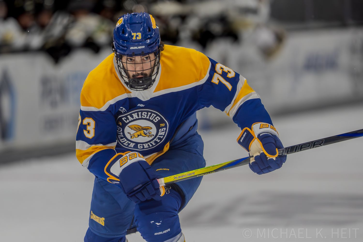 A hockey player in blue and gold uniform skates during competitive play.