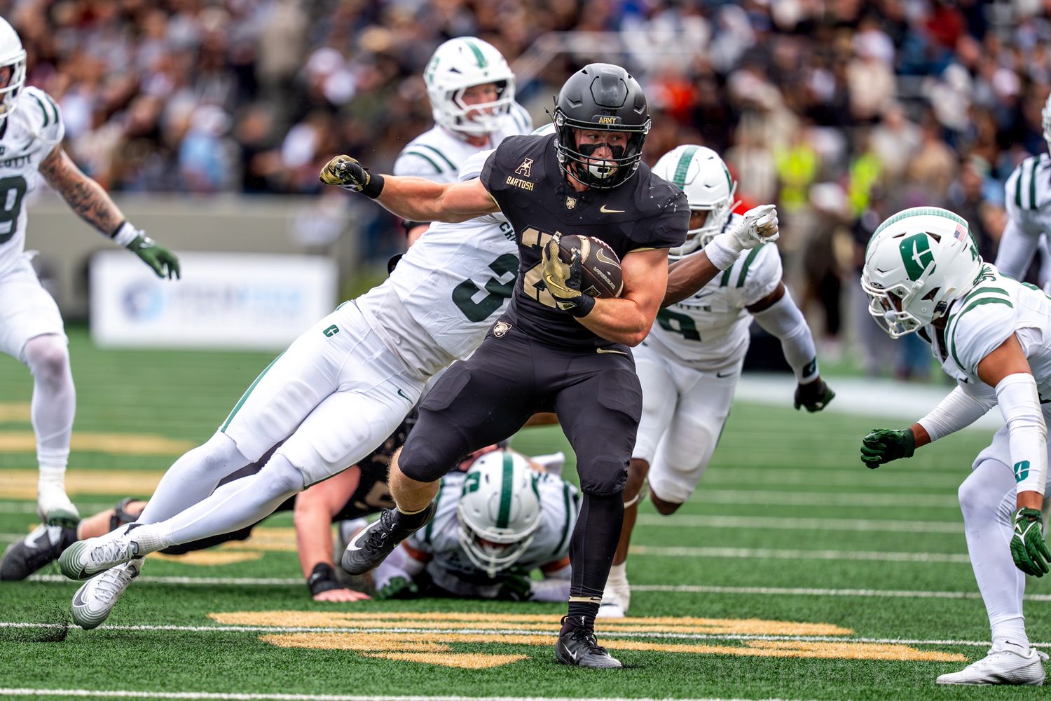 Football players from opposing teams collide during a tackle on the field.