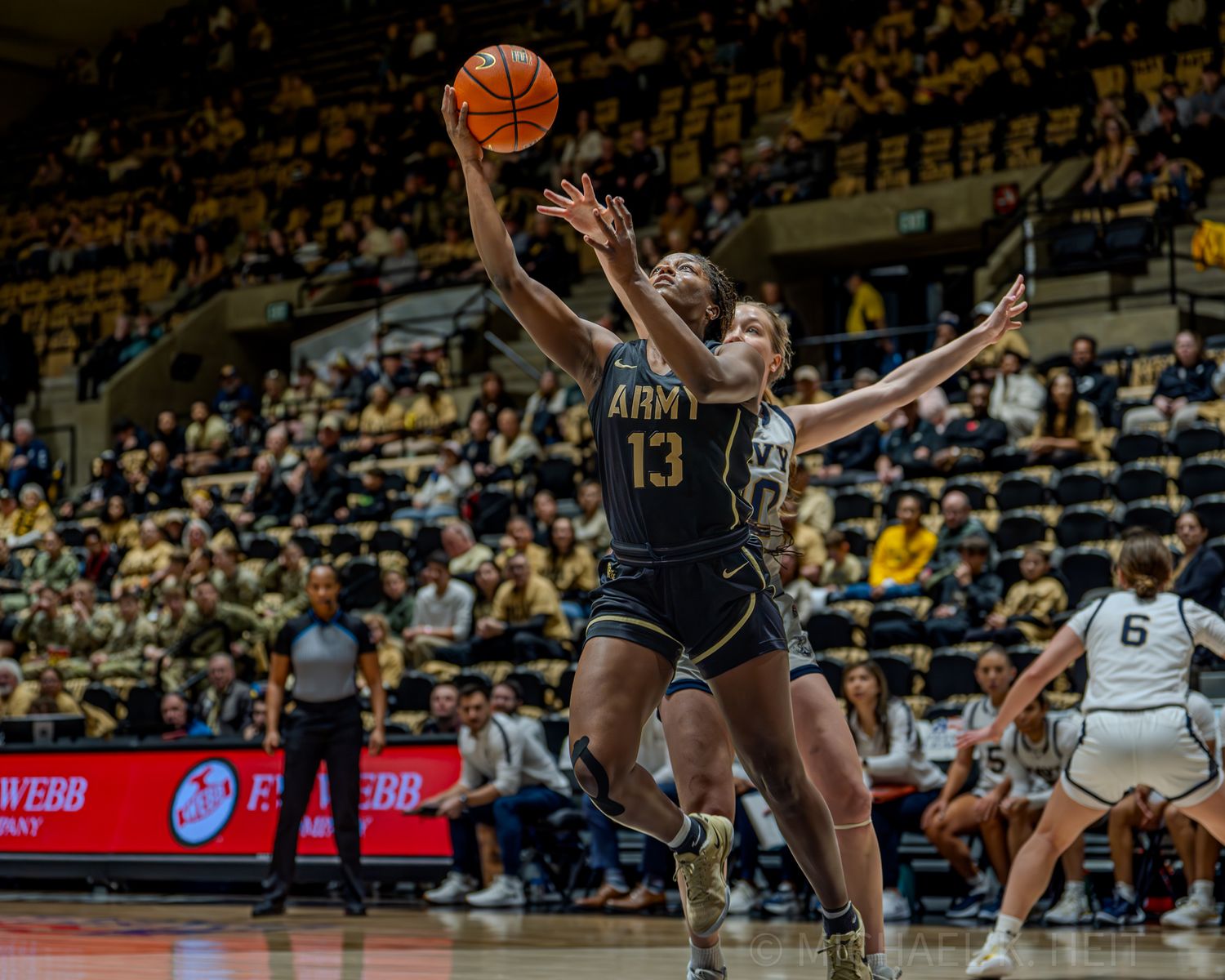 Basketball players from Army and Navy compete intensely for possession during a competitive match.