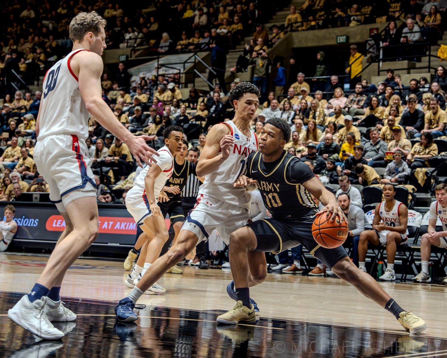 Basketball players compete intensely for ball possession during a competitive game on the hardwood court.