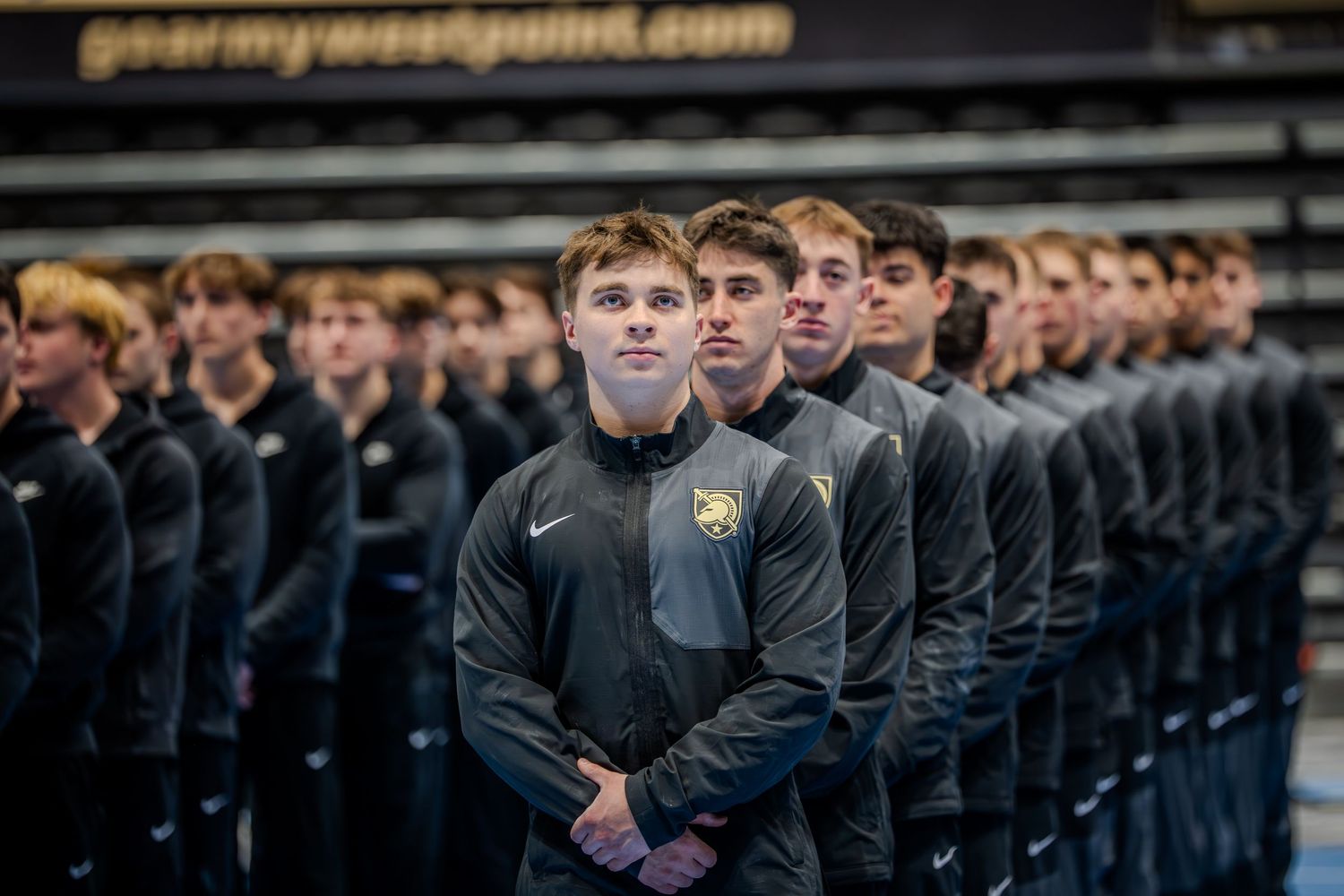West Point Army cadets in matching black uniforms stand in formation during an official military ceremony.