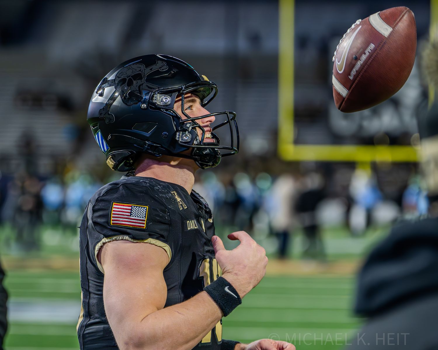 Football player in black uniform prepares to throw the ball during gameplay.