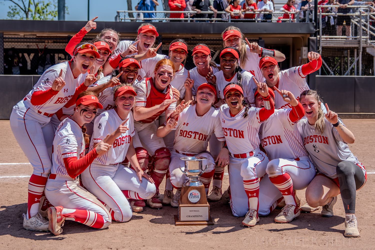Boston University softball team poses together with championship trophy on the field.