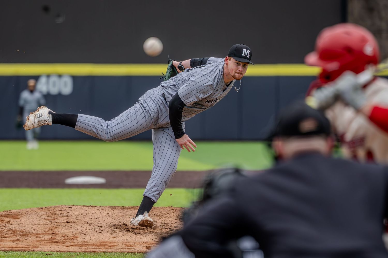Baseball player in gray uniform slides into base during intense gameplay moment at stadium.