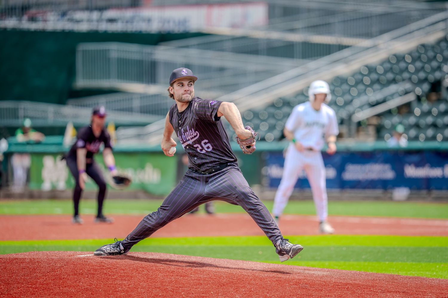 Baseball pitcher in dark uniform mid-throw on mound during a professional game in a stadium.