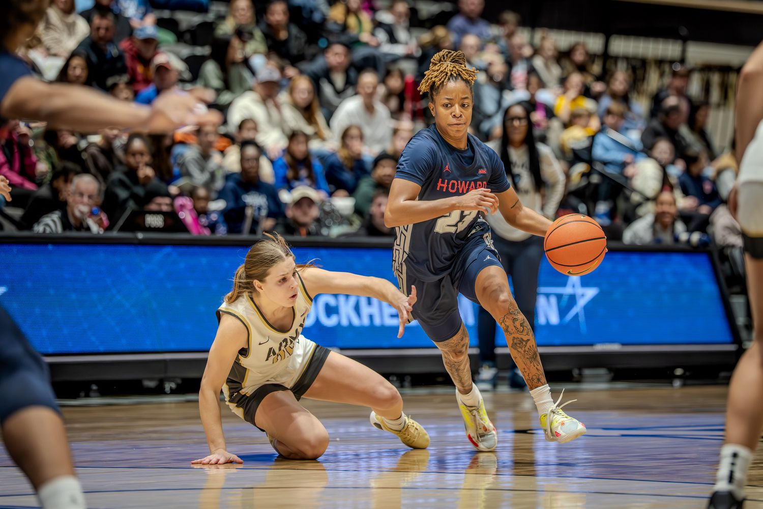 Basketball players dive for a loose ball during an intense game on the court.