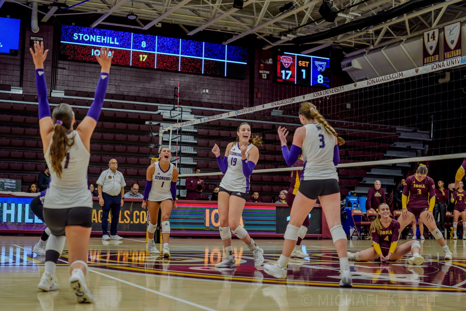 Wide angle view of volleyball court showing players in action during indoor game.