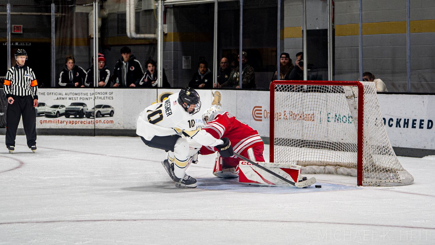 Hockey player attempts to score against goalie during intense game action.