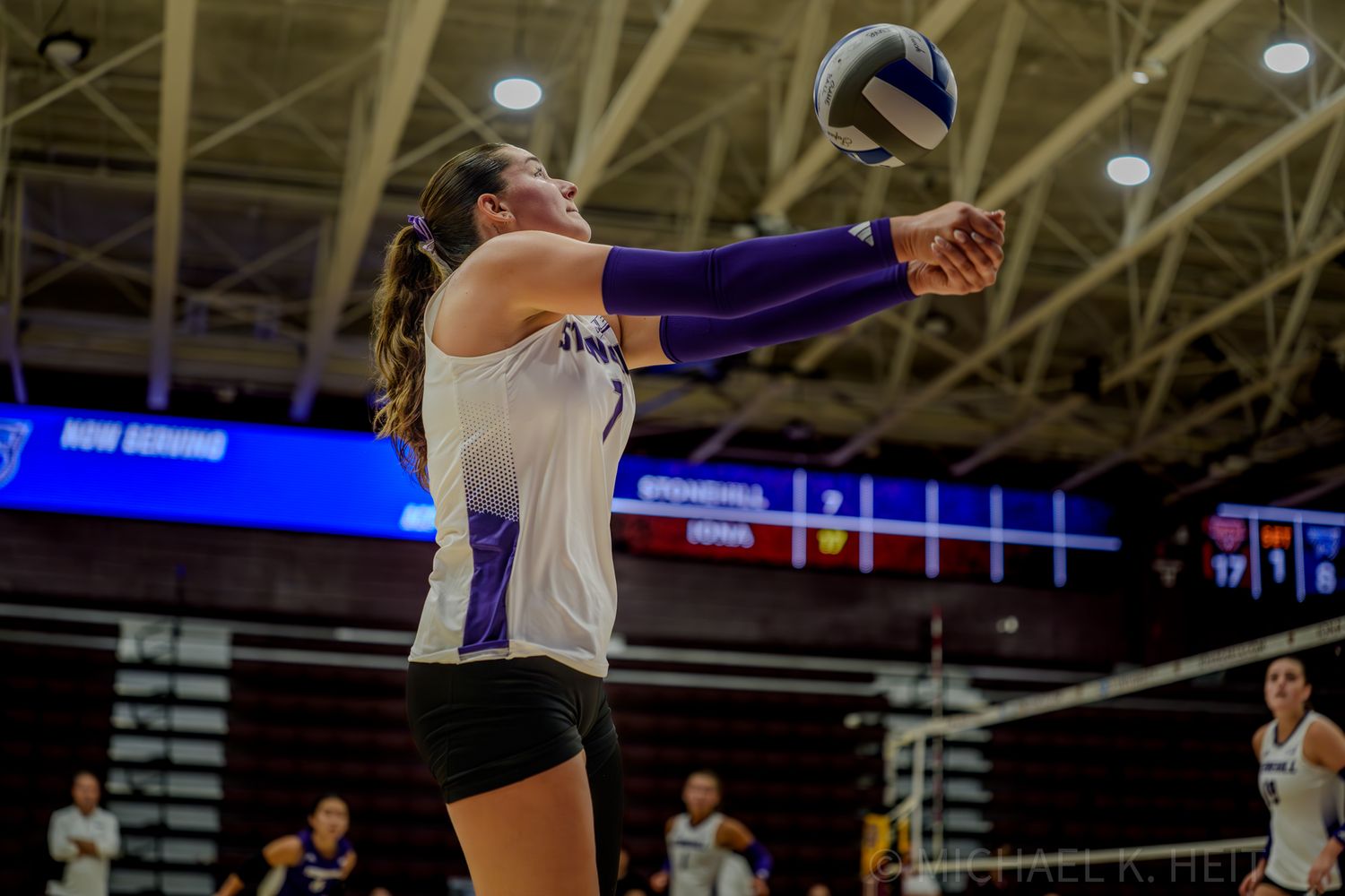 Volleyball player leaps high to spike the ball during competitive indoor match.