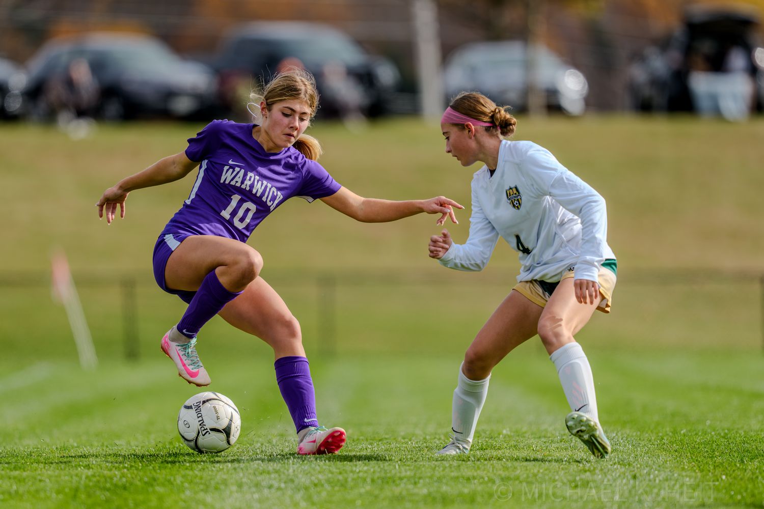 Soccer players in blue and white uniforms competing for ball control during match on grass field.