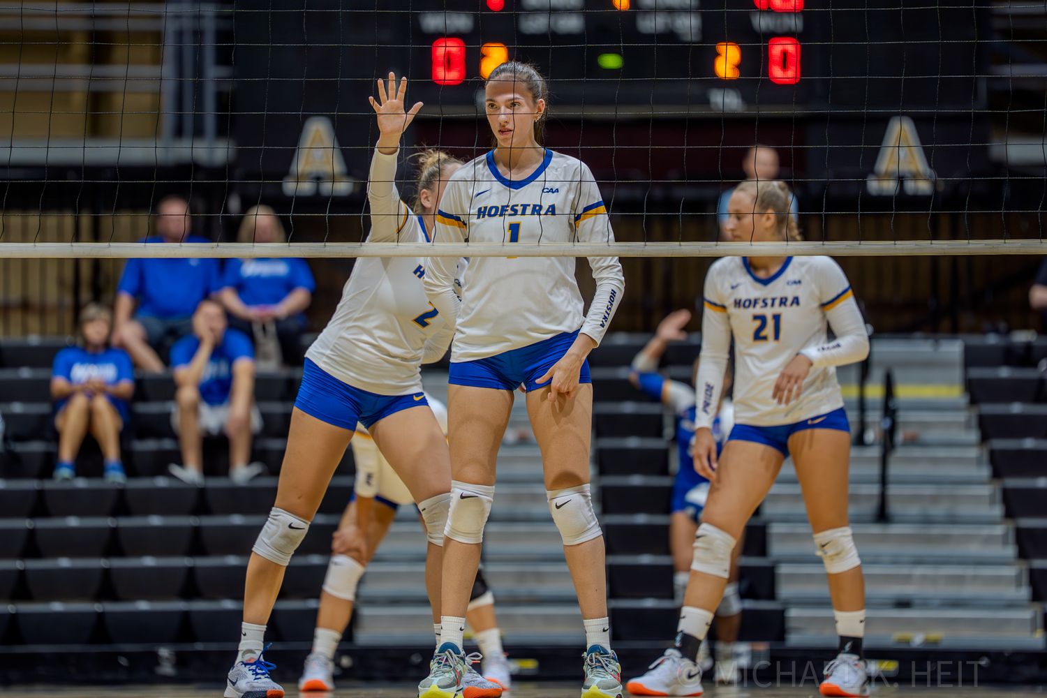 Three volleyball players position themselves for defensive coverage during a match.