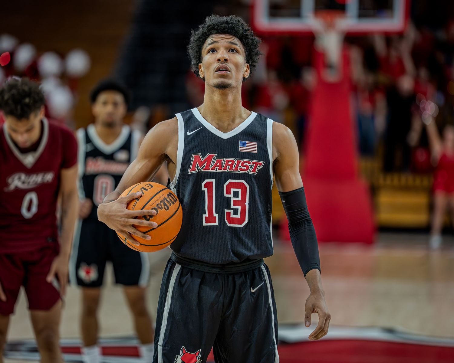 Basketball player in black jersey number 13 dribbles on court during intense game action.
